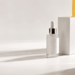 A skincare bottle and packaging arranged beside a camera lens on a clean studio surface, ready for a product photo shoot.